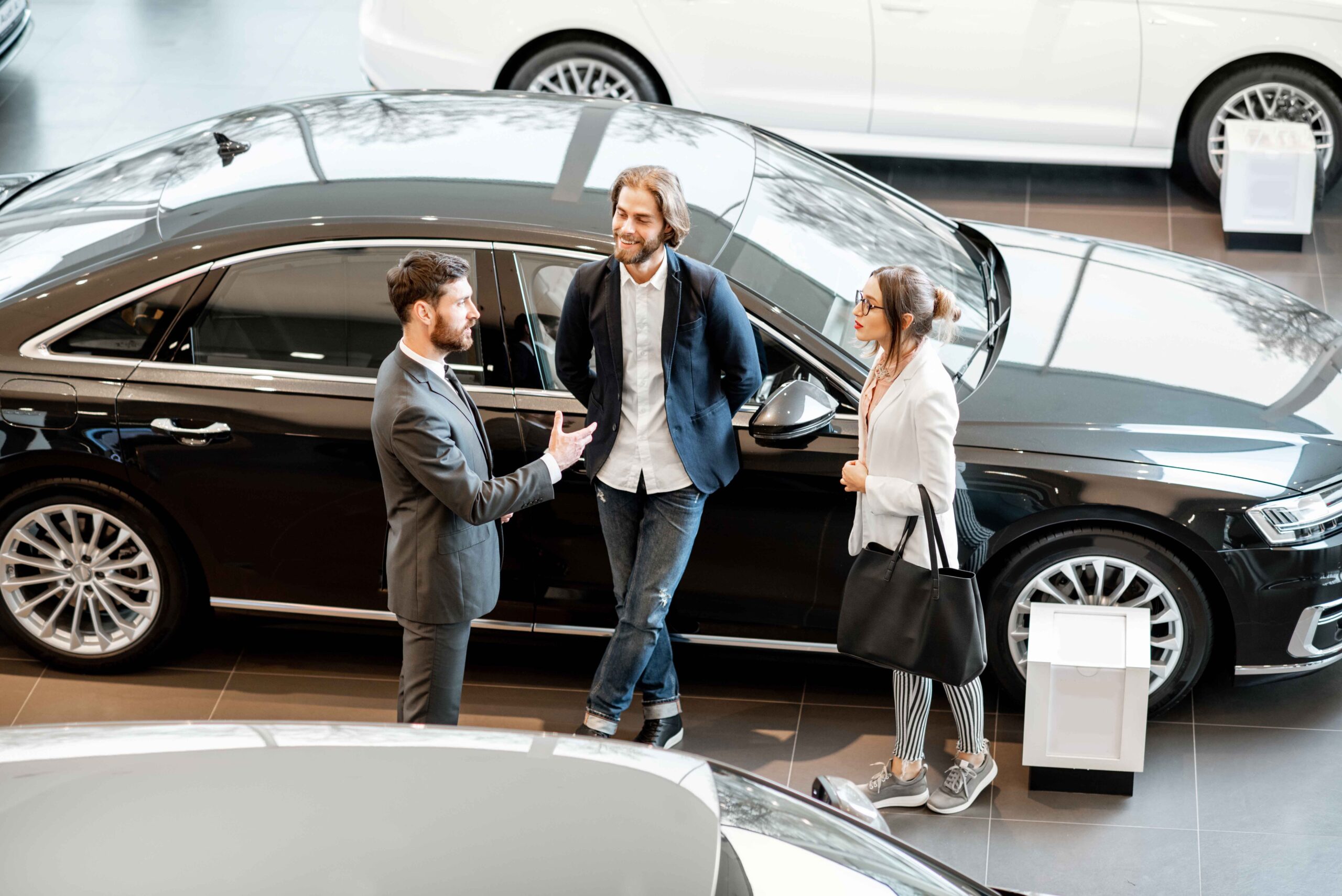 Business Couple With Salesperson In The Car Showroom